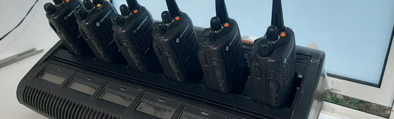Six black Motorola walkie-talkies on a black charging station.
